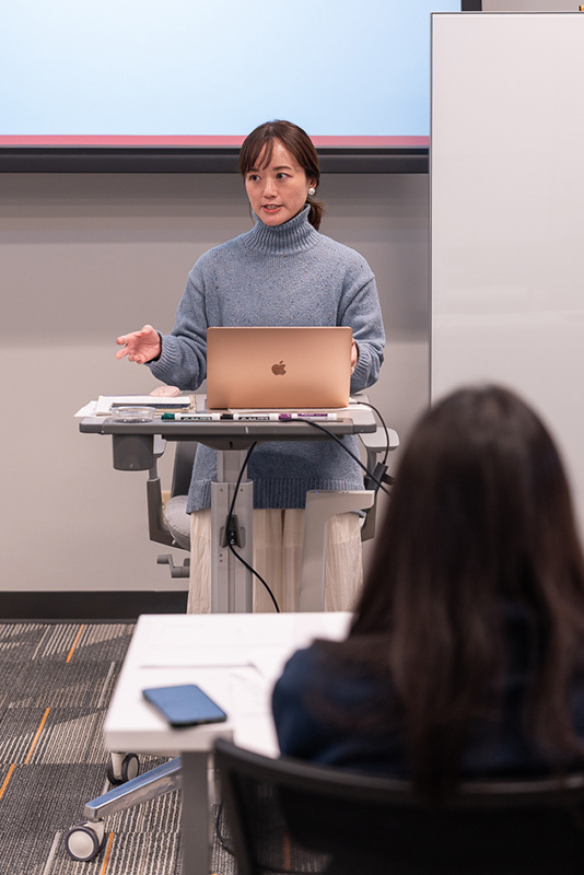 A woman teaches a Chinese language lesson in a classroom.