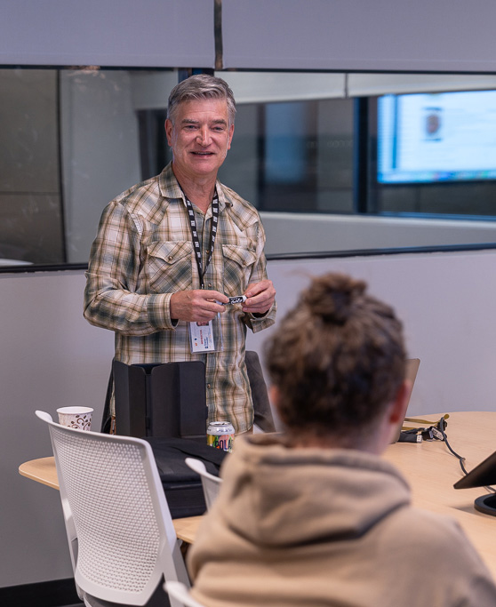A man teaches a French language lesson to as student in a small classroom.