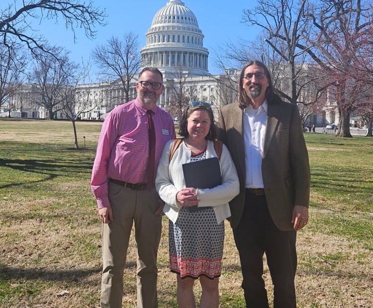 Two men and a woman standing in front of Capitol Hill