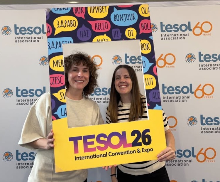 Two women holding up a frame that says TESOL for a selfie