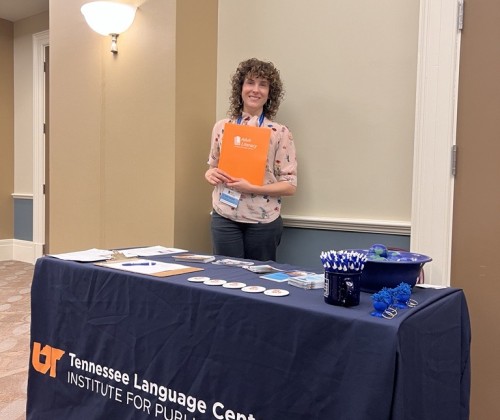 Woman holding a folder standing behind a table display