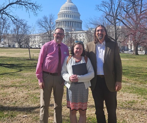 Two men and a woman standing in front of Capitol Hill