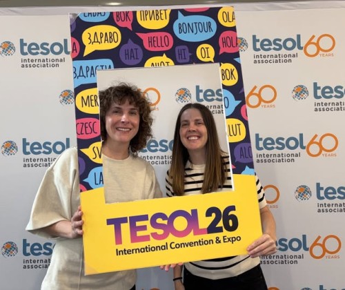Two women holding up a frame that says TESOL for a selfie