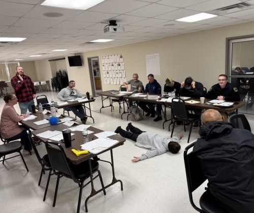 Class of officers deciding how to handle a suspect on the ground