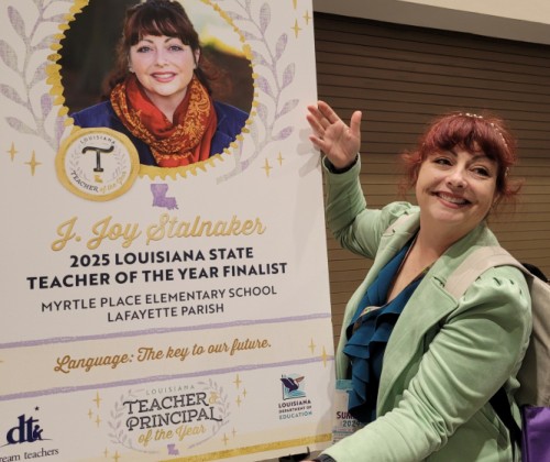 Woman in green blazer standing in front of poster with her nomination on it