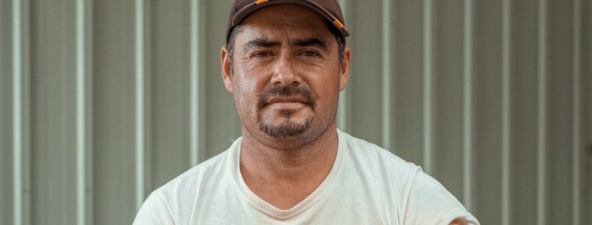 Man with mustache wearing a baseball cap and t-shirt