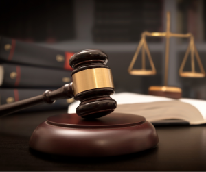 Gavel resting on a desk with a book and balance in the background to illustrate our Court Interpreter Workshop