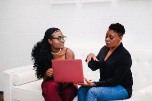 Two women sitting on a couch with a computer to illustrate custom language classes