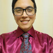 Man wearing glasses in a burgundy shirt and tie